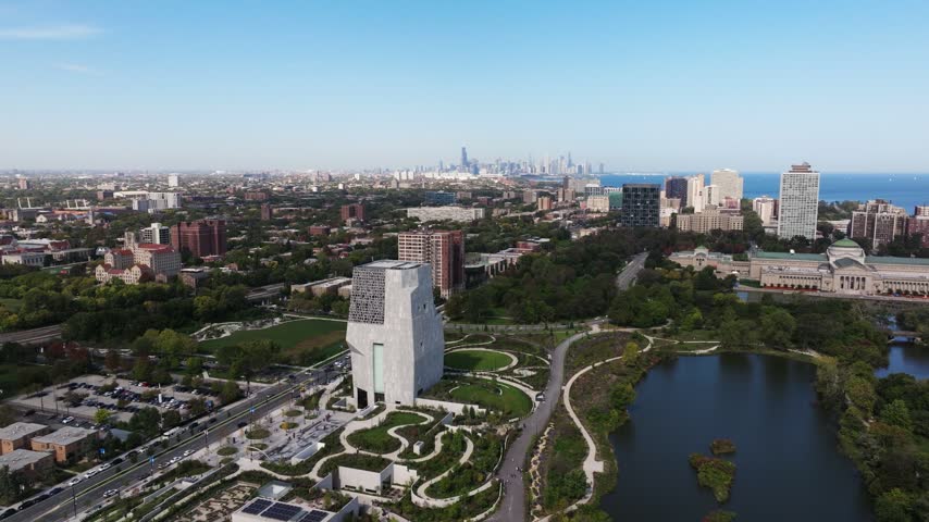 Aerial view of The Obama Presidential Center surrounded by lush parkland and winding pathways with the Chicago skyline in the distance, Chicago, Illinois, United States.