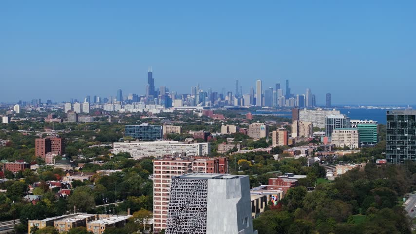 Aerial view of The Obama Presidential Center with the Chicago skyline in the background under a clear blue sky in Chicago, Illinois, United States.
