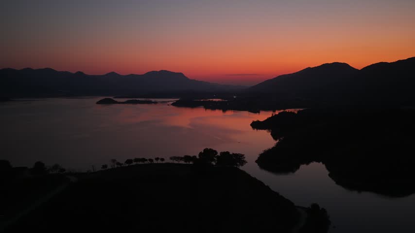 silhouette of mountains and lake at sunset