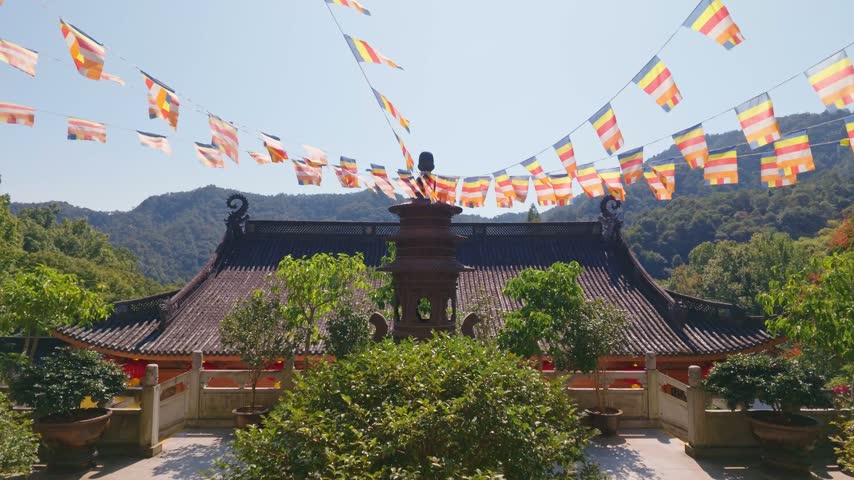 wide angle view of traditional architecture rooftop and buddhist flag decorations of Faxi Temple in the sunny morning, Hangzhou China