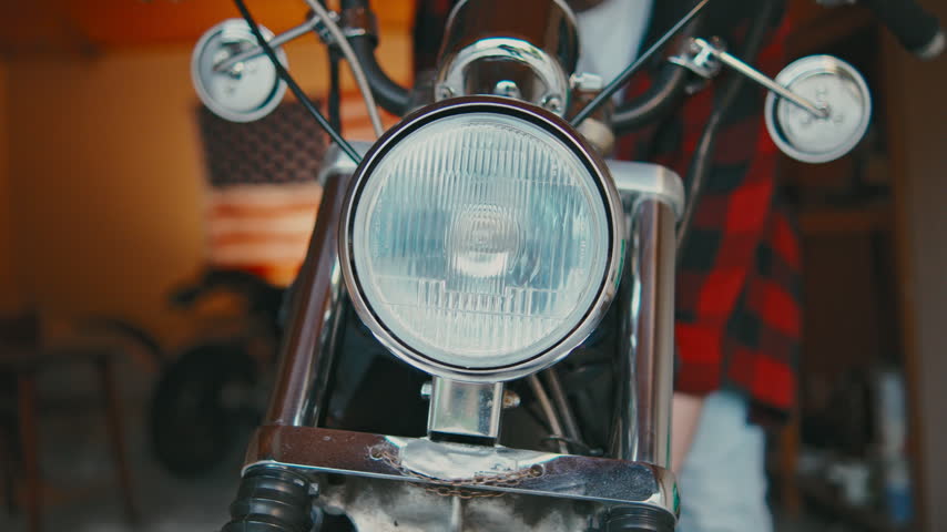 Motorcycle headlight shines brightly in a workshop during daytime hours