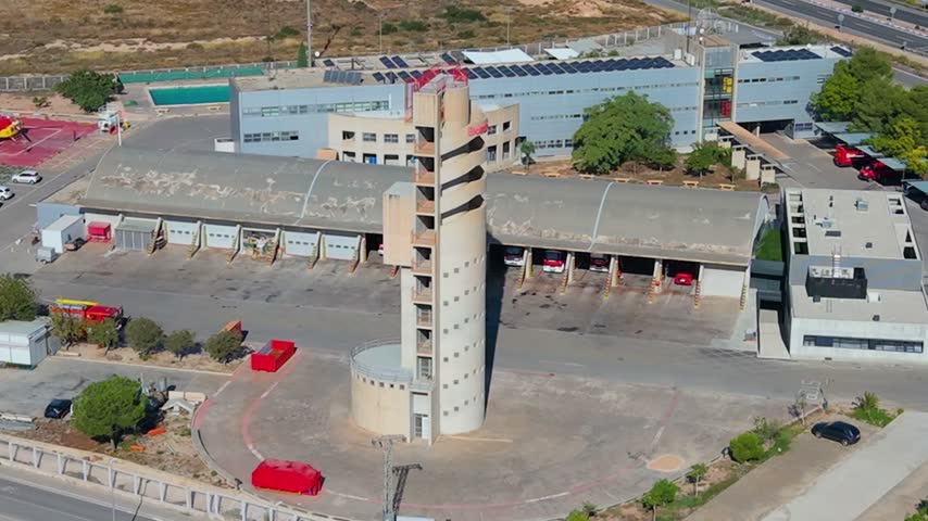 Aerial view of the fire station in Alicante featuring a tall training tower, fire truck bays, and surrounding facilities in Alicante, Valencian Community, Spain.