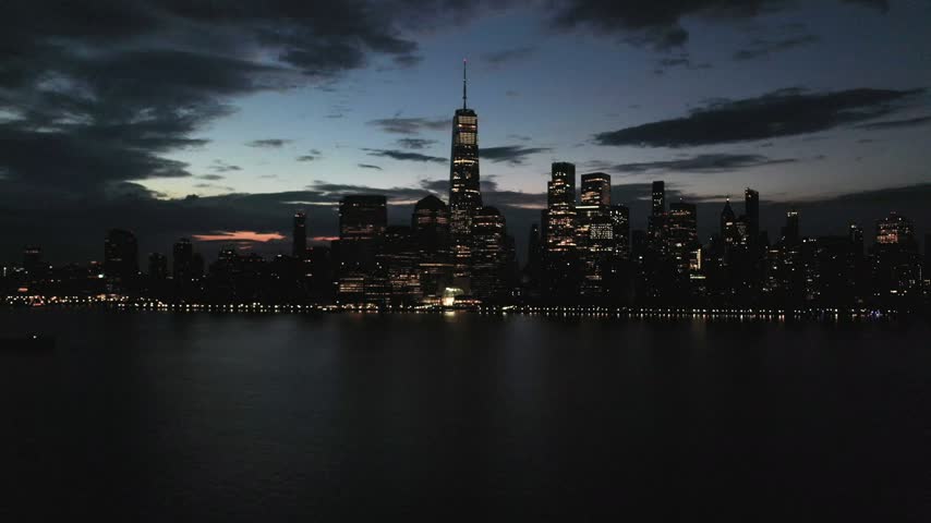 Aerial view of the illuminated Jersey City skyline reflecting over the Hudson River at night, Jersey City, New Jersey, United States.