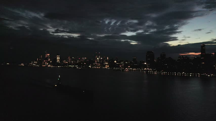 Aerial view of the illuminated Jersey City skyline at night with city lights reflecting on the Hudson River, Jersey City, New Jersey, United States.