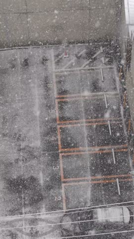 High angle view of a parking lot during a heavy snowstorm with snow accumulating fast.