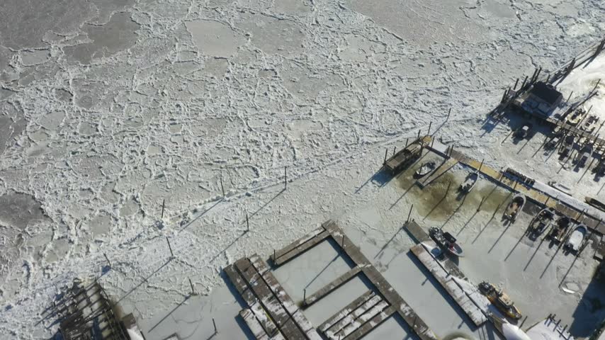 Aerial view of a frozen harbor with ice floes and boats docked at piers in Highlands, New Jersey, United States.