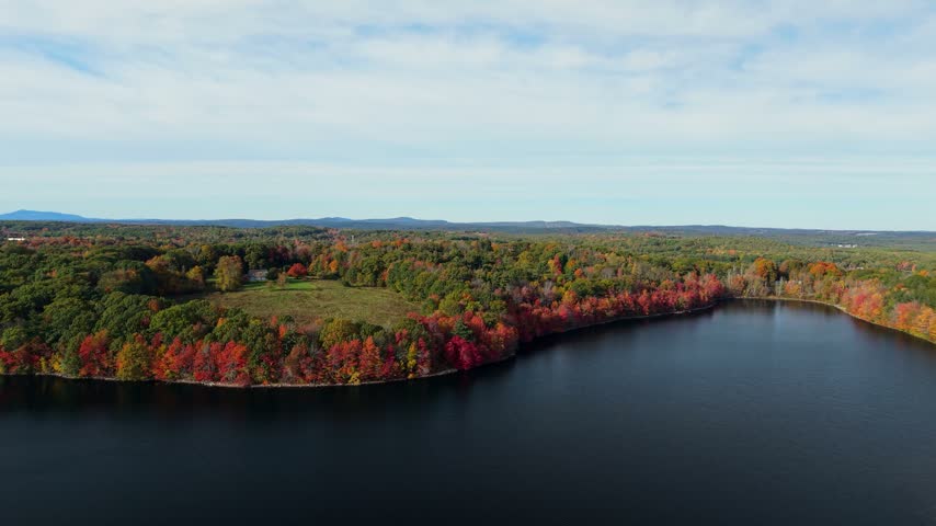 Aerial view of Mount Wachusett and vibrant autumn foliage surrounding a calm lake in Princeton, Massachusetts, United States.