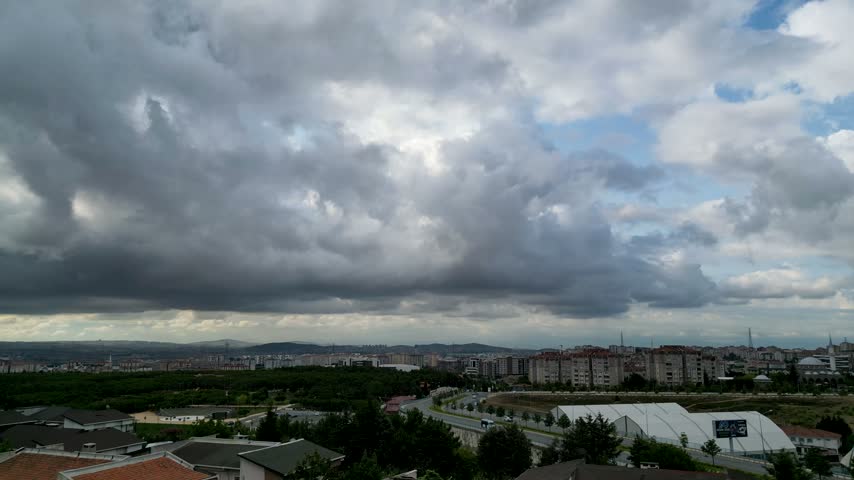 Timelapse of heavy dark overcast clouds rolling over a sprawling cityscape and suburban neighborhood
