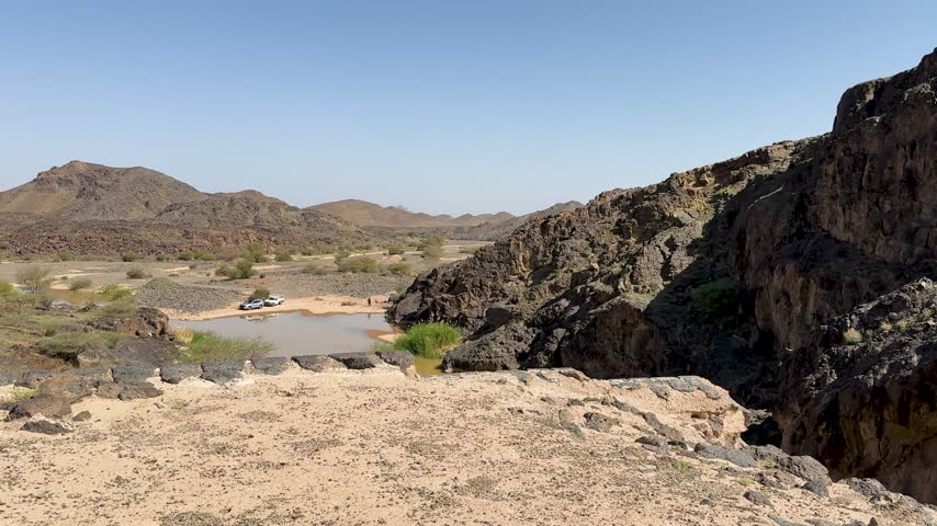 Ancient stone dam overlooking a scenic desert oasis with a water reservoir.