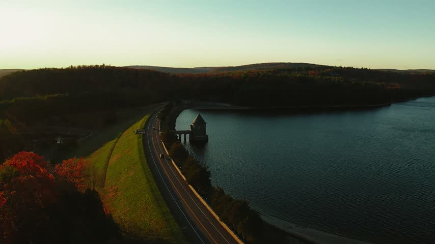 Barkhamsted Reservoir highway dam in Connecticut surrounded by brilliant fall foliage at sunset
