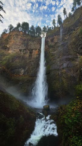Handheld vertical shot of the famous Multnomah Falls from Benson Bridge, showing where the water hits the ground below, in the Columbia River Gorge near Portland, Oregon, on a cold November morning.