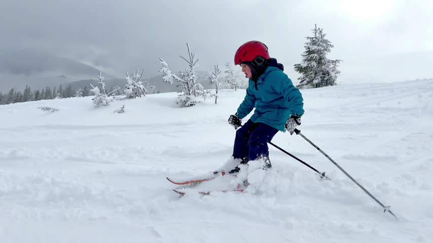 Active kid boy riding downhill,learn skiing in mountains alpine winter resort.little child enjoy extreme sport activities recreation,family luxury vacation.