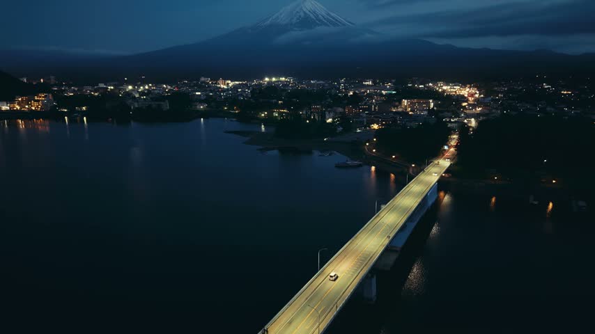 Nighttime Landscape of Mount Fuji Above Glowing City and Lake
