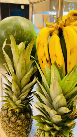 Close up vertical shot of fresh yellow bananas bunch, whole pineapples and green watermelons at five stars luxury hotel all inclusive buffet food counter in Sharm El Sheikh, Egypt. Tropical fruits.
