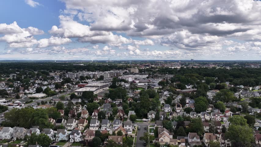 Rows of houses and leafy local roads form a broad residential landscape below a partly cloudy sky.