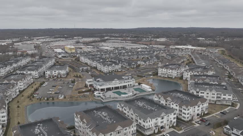 Aerial view of a townhouse development with winding roads, parked cars and winter landscaping in Holbrook, New York.