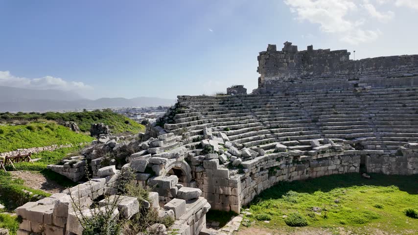 Xanthos ancient theater in Lycia near Kas, Antalya, Turkey, curved stone seating rows around a grassy orchestra among the ruins of the Lycian city