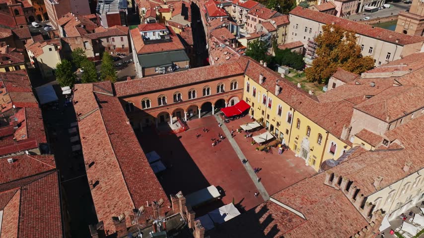 Aerial drone view of Piazza del Municipio in Ferrara, Italy, showcasing the historic square, elegant palace architecture, arcades, and surrounding old town cityscape.