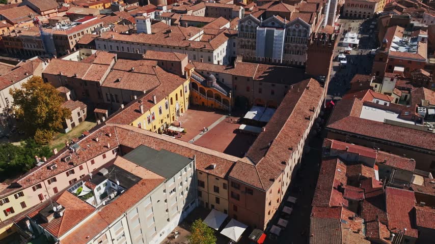 Aerial drone view of Piazza del Municipio in Ferrara, Italy, showcasing the historic square, elegant palace architecture, arcades, and surrounding old town cityscape.