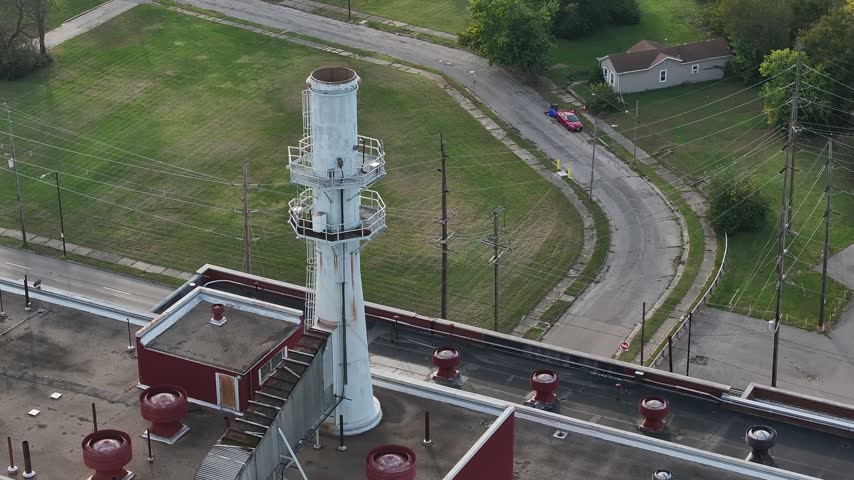 Aerial view of an industrial chimney rising from a flat roof with surrounding roads and greenery in Hamilton, Ohio, United States.
