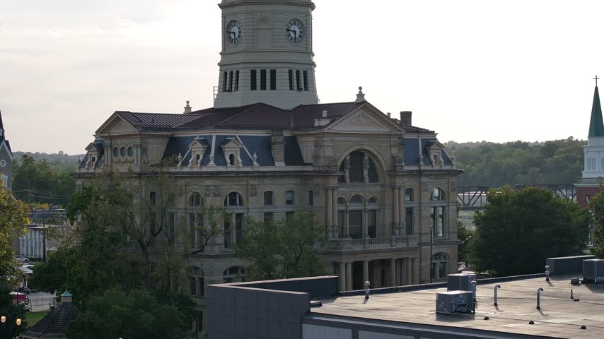 Aerial view of the historic Butler County Courthouse with its prominent clock tower and stone architecture surrounded by trees and urban rooftops in Hamilton, Ohio, United States.