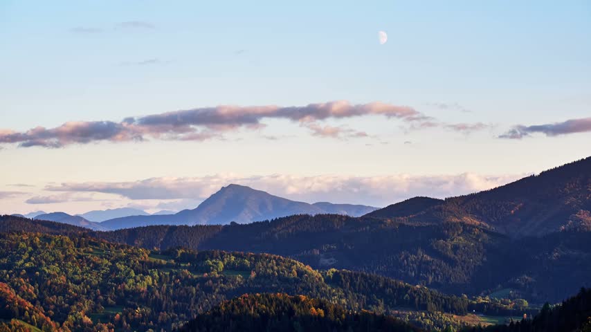 Timelapse of autumn mountain landscape with moon during twilight
