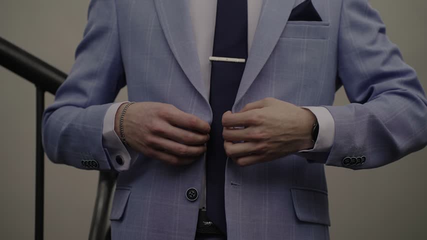 A man buttons his jacket. A businessman is getting ready for a meeting