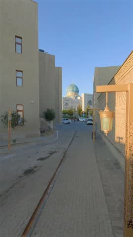 Vertical view along a brick lined lane toward the Islamic Civilization Center in Tashkent, Uzbekistan. Its turquoise dome rises beyond the Old Town buildings.