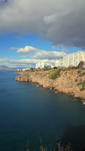 Dramatic clouds over Antalya cliffs and Mediterranean coastline with urban buildings