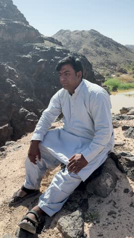 Man sitting and relaxing on a scenic rocky mountain landscape.