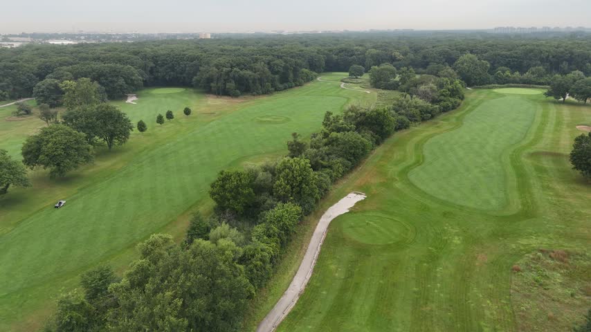 Aerial view of rolling golf course fairways lined with trees. Filmed in River Grove, Illinois.