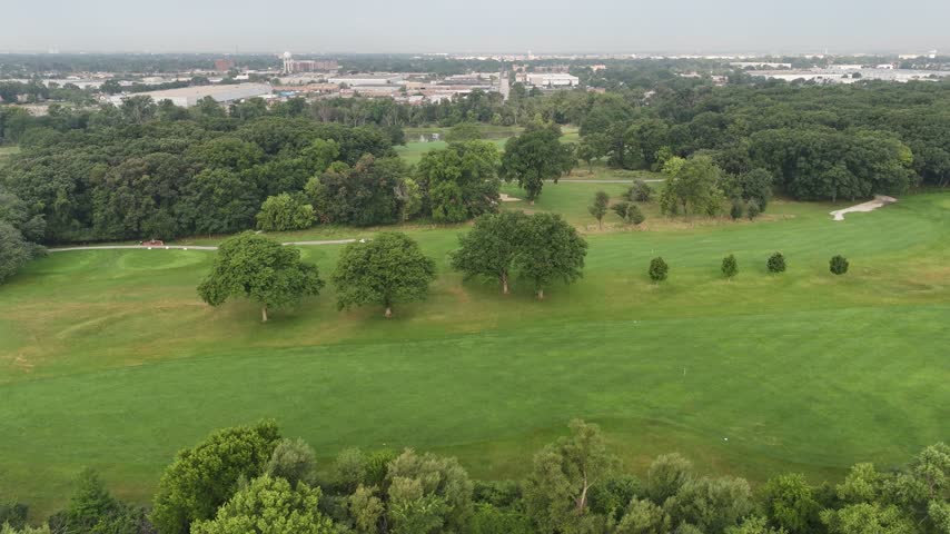 Aerial view of open golf fairway with clusters of trees. Filmed in River Grove, Illinois.
