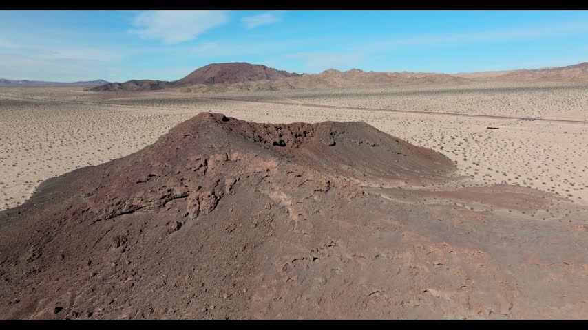 Drone flying over the rim of Amboy Crater volcanic cinder cone in the Mojave Desert