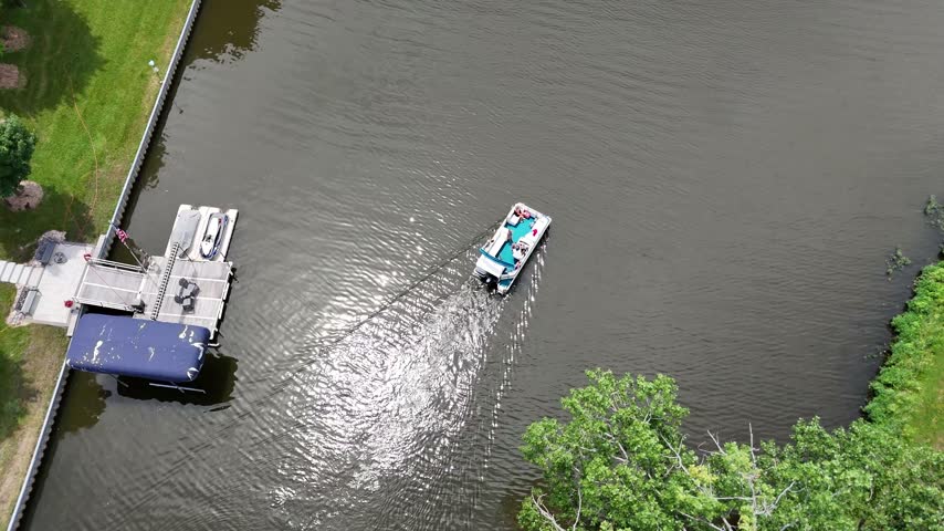 Overhead view of two boats crossing a lake near a dock. Filmed in Sandwich, Illinois.