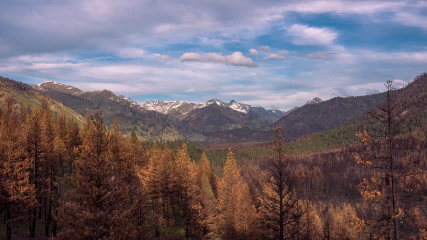 Stanley Idaho mountain landscape timelapse showcases rolling clouds sweeping across snowy summits dense pine forests and colorful autumn valleys