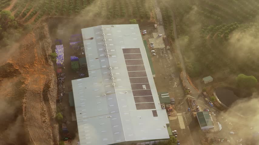 Aerial view of industrial building with solar panels on the roof surrounded by olive groves in El Campillo, Andalusia, Spain.