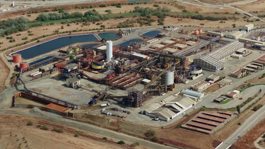 Aerial view of the Mina Cobre Las Cruces industrial facility with processing plants, storage tanks, and water ponds in the arid landscape of Gerena, Andalucia, Spain.