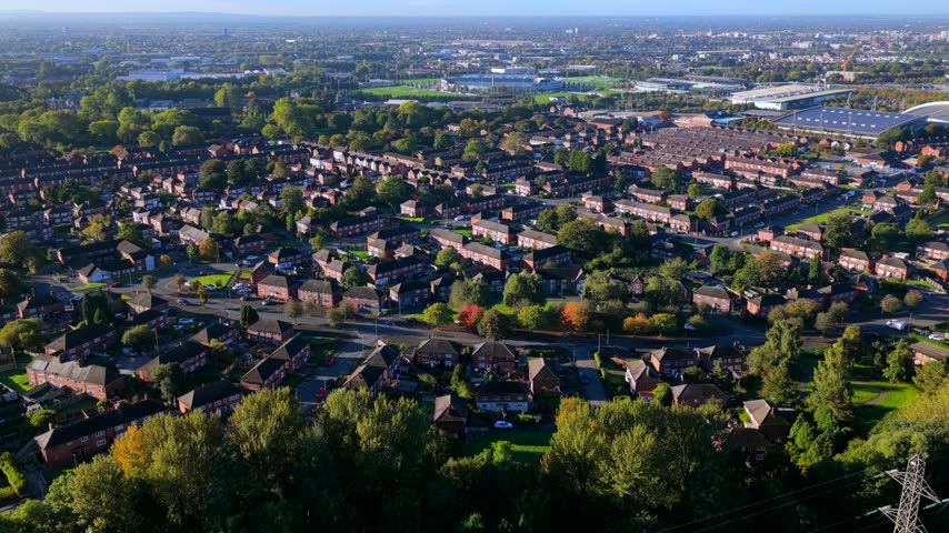 An aerial view in the morning shows Clayton Vale Park, Philips Park, housing, roads, trees and power lines in East Manchester, United Kingdom.