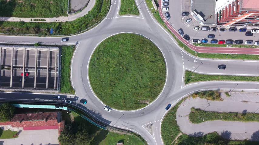 Aerial view of traffic flow around a roundabout with cars moving on the road in Milan, Lombardy, Italy.
