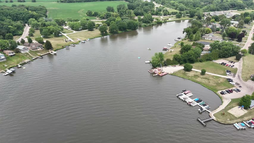 Aerial view of a calm river channel lined with docks and boats. Filmed in Sandwich, Illinois.