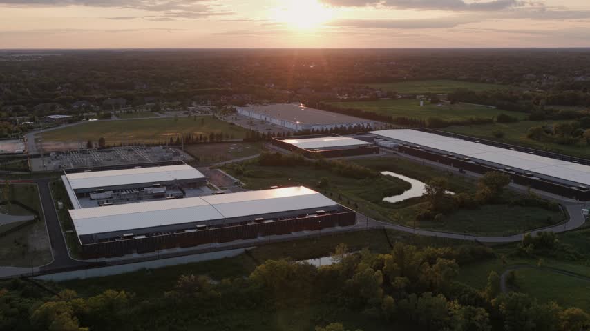 Aerial view of data center complex with large industrial buildings and green spaces during golden hour in Hoffman Estates, Illinois, United States.