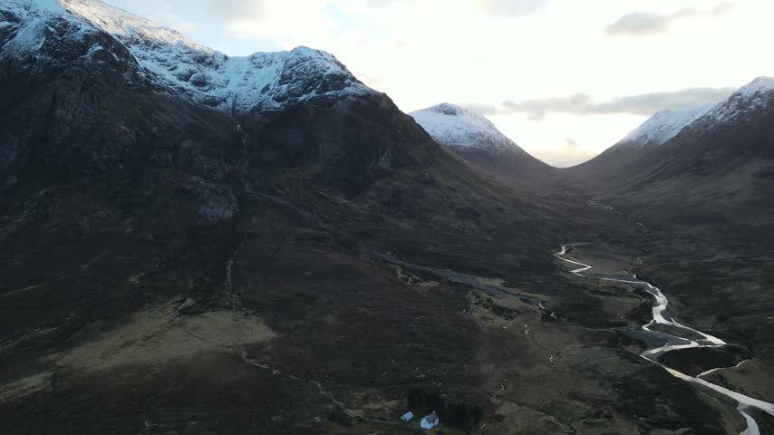 Aerial view of Glencoe valley with snow-capped mountains and a winding river in Glencoe, Scotland, United Kingdom.