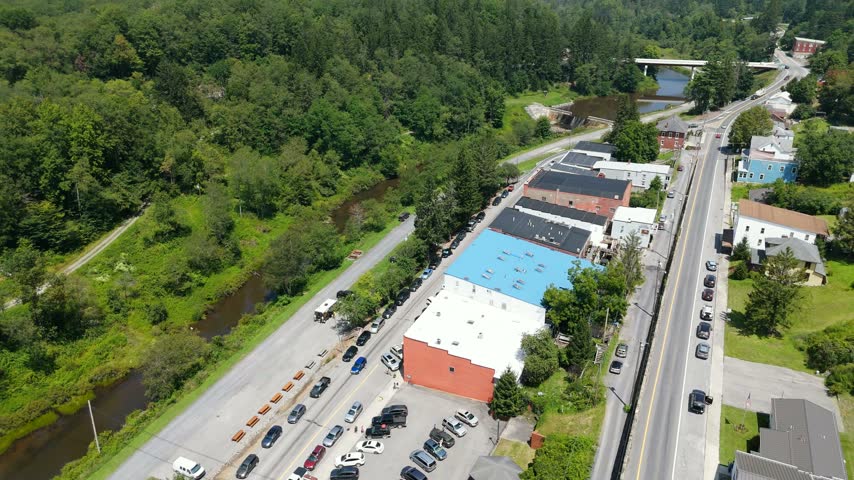 High aerial drone view looking down a small mountain town main street lined with brick buildings with a river running alongside, Thomas, West Virginia, USA.