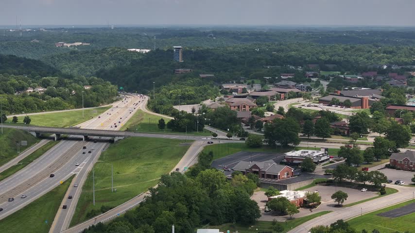 Aerial view of a highway interchange surrounded by lush green trees and suburban buildings in Crestview Hills, Kentucky, United States.