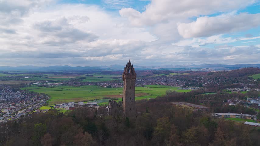 Aerial view of The National Wallace Monument surrounded by lush green fields and woodlands in Stirling, Scotland, United Kingdom.