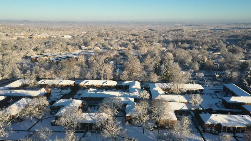 Aerial view of snow-covered residential buildings and trees in a quiet neighborhood during winter in Summit, New Jersey, United States.