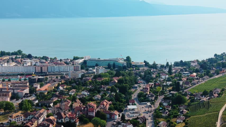 Aerial view of Nestle S.A. Headquarters overlooking Lake Geneva with surrounding urban architecture and vineyards in Vevey, Vaud, Switzerland.
