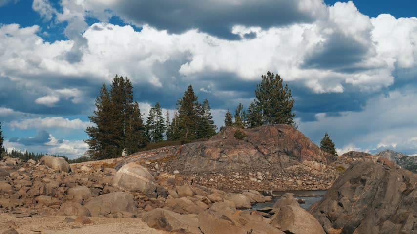 Pine trees grow atop rocky granite formations in a high alpine California landscape