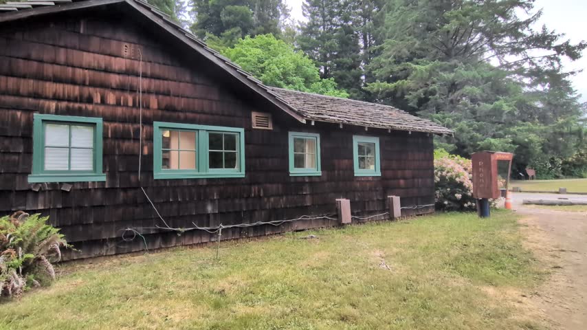 Historic wooden shingle park building and wooden phone booth nestled in a tranquil redwood forest setting.