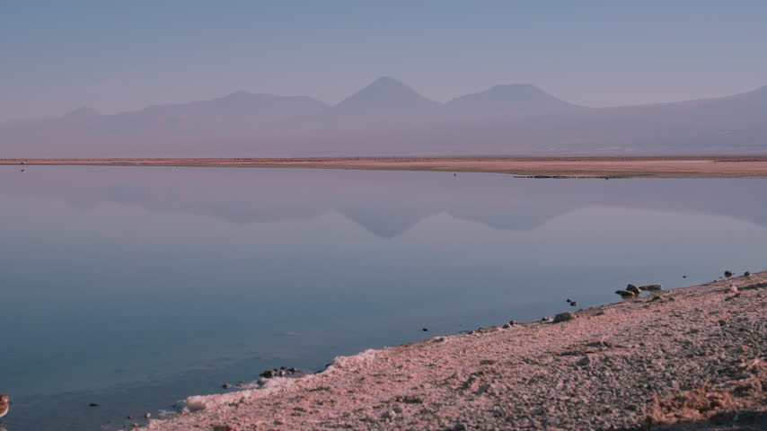 Calm Blue Lagoon Perfectly Reflecting Distant Volcanoes in the Atacama Desert, Chile   